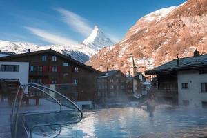 Jeune homme nager à l'intérieur le luxe infini en plein air bassin avec un incroyable vue à le Matterhorn de pointe dans zermatt, Suisse. photo