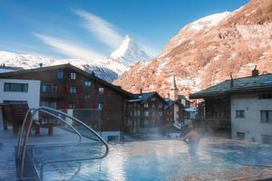 Jeune homme nager à l'intérieur le luxe infini en plein air bassin avec un incroyable vue à le Matterhorn de pointe dans zermatt, Suisse. photo