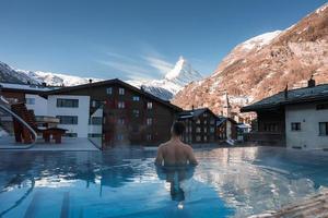 Jeune homme nager à l'intérieur le luxe infini en plein air bassin avec un incroyable vue à le Matterhorn de pointe dans zermatt, Suisse. photo