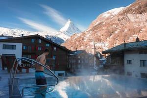 Jeune homme nager à l'intérieur le luxe infini en plein air bassin avec un incroyable vue à le Matterhorn de pointe dans zermatt, Suisse. photo