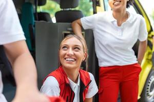 deux femelle infirmières par le ambulance. ambulanciers par le ambulance, souriant. photo