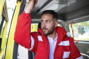 Jeune homme, paramédical séance sur le côté de le ambulance. ambulanciers par le ambulance. avoir prêt à répondre à urgence appel photo