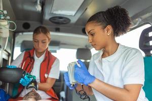 paramédical en utilisant défibrillateur aed dans conduite une de base cardiopulmonaire réanimation. urgence se soucier assistant en mettant silicone Manuel réanimateurs dans un ambulance. photo