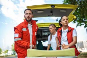 Jeune ambulanciers en mouvement ambulance tendeur de voiture dans une dépêche toi. ambulanciers dans uniforme prise tendeur en dehors le ambulance voiture photo