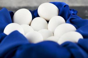 Œufs de poule crus blancs avec sur une nappe bleue photo