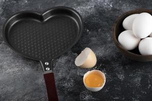 bol d'oeufs blancs et de jaune à côté d'une casserole en forme de cœur photo