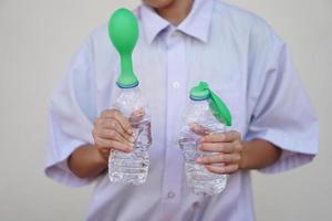 étudiant étude science expérience, tenir deux bouteilles avec vert des ballons sur le Haut de bouteilles. concept, science expérience à propos réaction de chimique substance, le vinaigre et cuisson un soda. photo