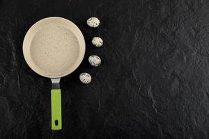 trois œufs de caille autour d'une casserole vide photo