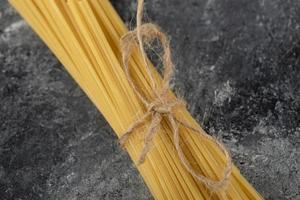 spaghettis secs attachés avec une corde sur un fond de marbre photo