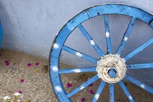 vieux en bois bleu roue, proche en haut vue de le roue. le vieux en bois roue sur le Contexte de le bleu mur de le maison photo