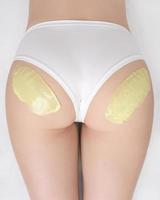 Haut vue vert chaud la cire sur fesses de svelte femme tandis que elle mensonge vers le bas sur canapé. épilation processus photo