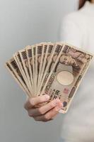 main de femme tenant la pile de billets de banque en yen japonais. mille yens d'argent. trésorerie du japon, impôt, économie de récession, inflation, investissement, finances et concepts de paiement d'achat photo