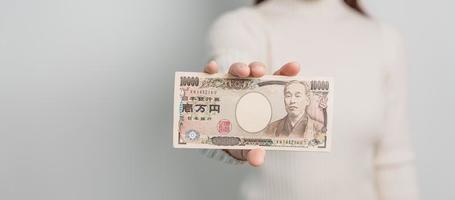 main de femme tenant la pile de billets de banque en yen japonais. mille yens d'argent. trésorerie du japon, impôt, économie de récession, inflation, investissement, finances et concepts de paiement d'achat photo