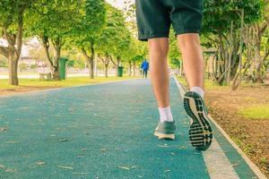 fonctionnement pieds Masculin dans coureur le jogging exercice avec vieux des chaussures pour santé perdre poids concept sur Piste caoutchouc couverture bleu Publique parc. copie espace ajouter texte. ancien tonifiant. photo