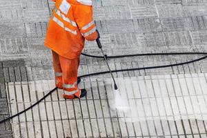 ouvrier nettoyage une rue trottoir avec haute pression l'eau jet. copie espace photo