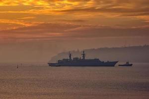 militaire bataille navale en utilisant remorqueurs aller à le Port à le lever du soleil temps photo