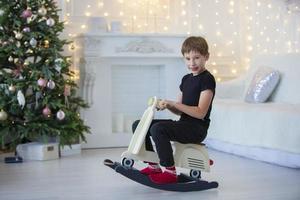 Beau peu garçon dans décontractée vêtements est en jouant dans le Noël chambre. photo