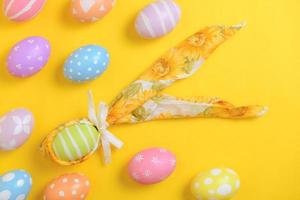 coloré peint Pâques Oeuf décoré avec une serviette de table dans le forme de une lapin sur une Jaune Contexte photo