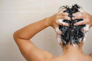 une homme est la lessive le sien cheveux avec shampooing photo