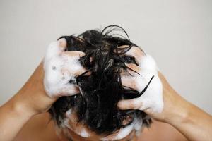 une homme est la lessive le sien cheveux avec shampooing photo