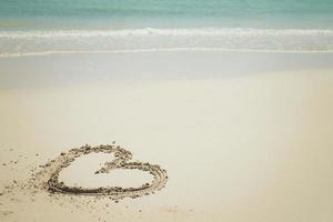 en forme de coeur plage avec brillant bleu l'eau. photo