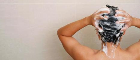 une homme est la lessive le sien cheveux avec shampooing photo