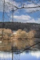 rivière couler avec reflets de bleu ciel et des arbres dans printemps avec visible Vilnius télévision la tour sur le Contexte photo