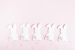 content Pâques blanc papier carton lapins dans une rangée et cœurs sur rose Contexte Haut vue photo