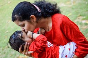 aimant maman porter de sa bébé à société parc. brillant portrait de content maman en portant enfant dans sa mains. mère étreindre sa peu 9 mois vieux fils. photo