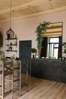 le intérieur de une pays maison fabriqué de bois dans le scandinave style. une bar table avec chaises et une poitrine de tiroirs avec une grand miroir au dessus il photo