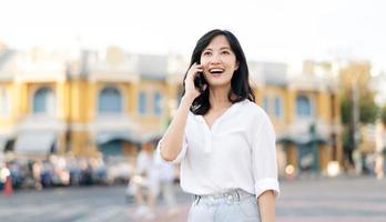 portrait magnifique Jeune asiatique femme avec intelligent mobile téléphone autour Extérieur rue vue dans une été journée photo