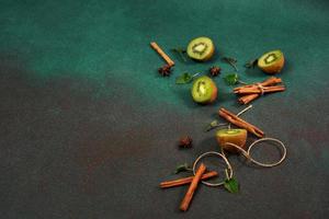 tranches de frais, juteux kiwi sur une vert Contexte. décoré avec cannelle des bâtons, Badyan, menthe feuilles. fruité décoré Contexte photo