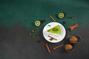 cheesecake avec kiwi, cannelle bâton et feuilles menthe sur une vert Contexte. copie cpase pour texte photo