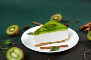 cheesecake avec kiwi, cannelle bâton et feuilles menthe sur une vert Contexte. copie cpase pour texte photo