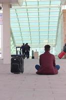 homme séance avec le sien retour à le train station avec le sien les valises photo
