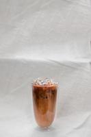 Verre de café glacé au lait sur fond de tissu blanc photo
