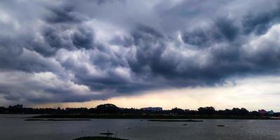 une nuageux ciel plus de une lac, blanc ciel avec noir nuage photo