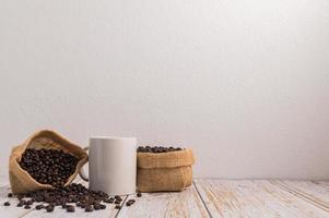 Une tasse de café et des sacs de grains de café sur une table en bois photo