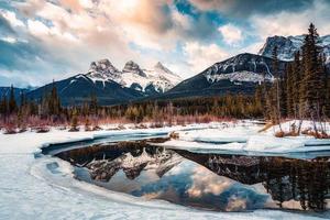 Trois sœurs montagnes avec neige couvert sur arc rivière réflexion dans le Matin sur hiver à Canmore photo