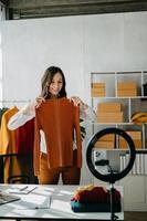 mode blogueur concept, Jeune asiatique femmes vente vêtements sur vidéo streaming.startup petit affaires PME, en utilisant téléphone intelligent ou tablette prise recevoir et vérification photo