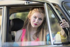 une magnifique blond fille avec longue cheveux regards en dehors de le voiture la fenêtre. photo