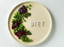 Une assiette avec une salade avec le mot régime sur un fond texturé blanc photo