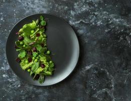 Salade diététique de feuilles de laitue, d'épinards et de pois verts sur fond sombre photo