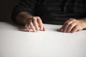 Homme méconnaissable dans une position familière assis à une table vide blanche photo