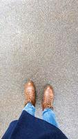Vue de dessus selfie des pieds d'une femme en bottes d'automne marron sur l'asphalte humide après la pluie