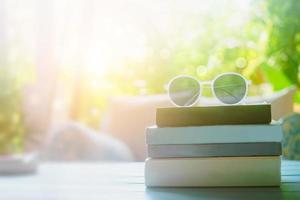 Livres sur une table avec des lunettes de soleil sur le dessus dans une chambre de villégiature en vacances, lecture et détente concept d'éducation thérapeutique