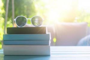 Livres sur une table avec des lunettes de soleil sur le dessus dans une chambre de villégiature en vacances, lecture et détente concept d'éducation thérapeutique photo