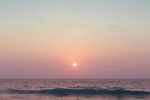 vagues de la mer de l'océan coloré pendant un lever ou coucher de soleil rose avec le soleil en arrière-plan photo