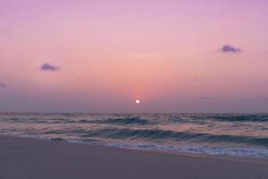 vagues de la mer de l'océan coloré pendant un lever ou coucher de soleil rose avec le soleil en arrière-plan photo