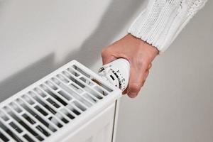 femme dans chaud chandail ajustement Température sur chauffage radiateur photo